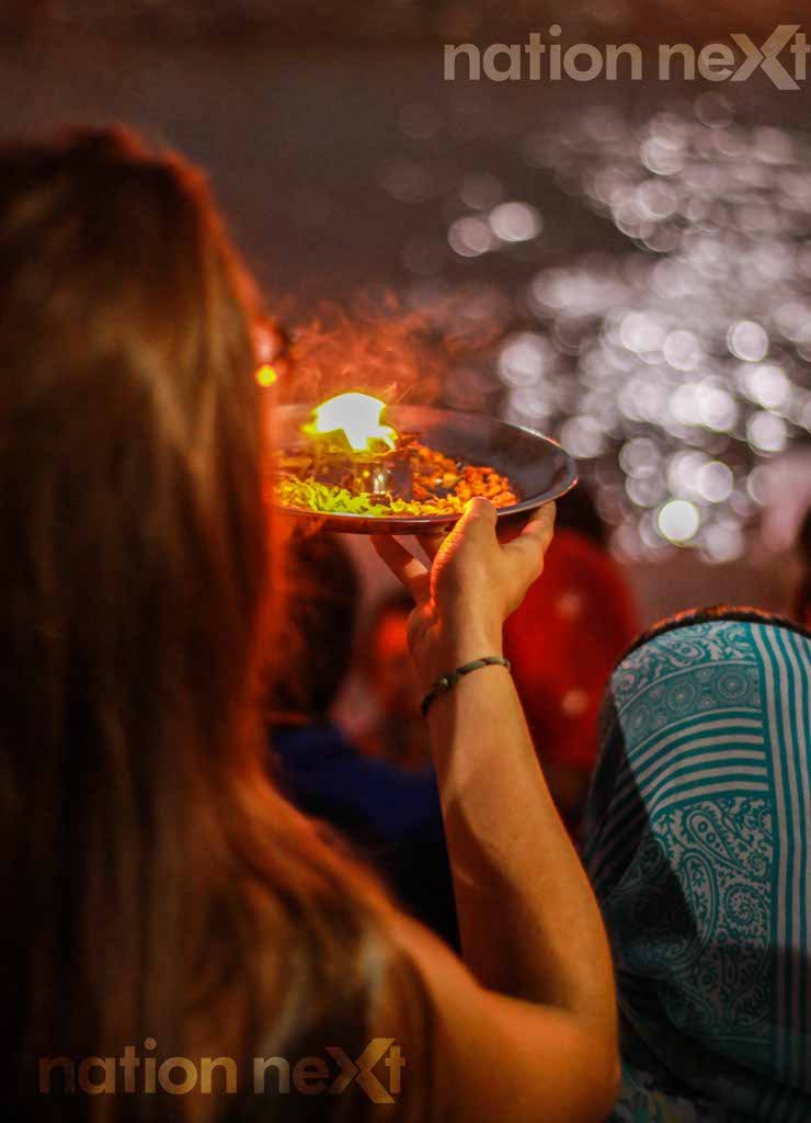 A foreigner carries out the Ganga Aarti in the evening hours at Triveni Ghat at Rishikesh