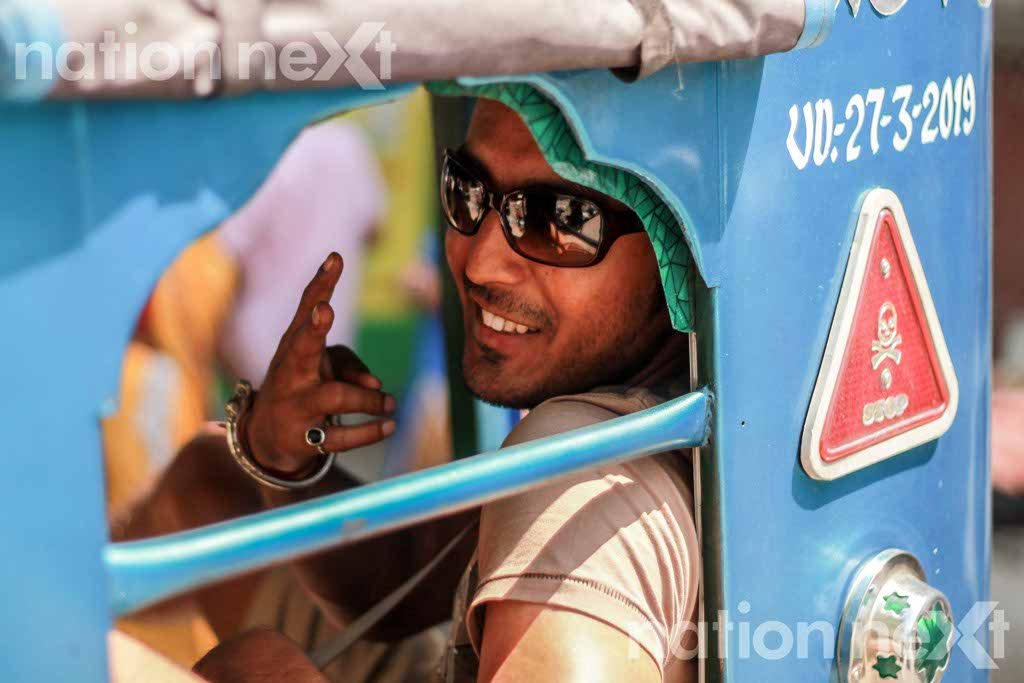 A tourist sitting in a Tuk-tuk (auto) poses for the photographer at Rishikesh